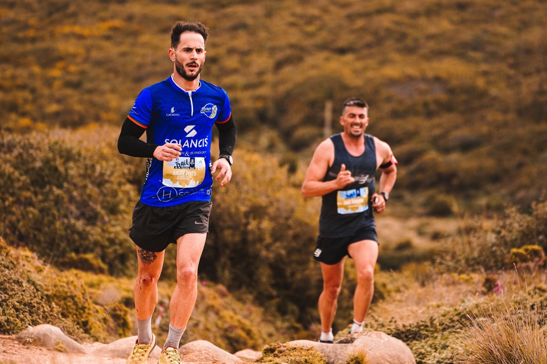 two trail runners moving through a forest trail during training