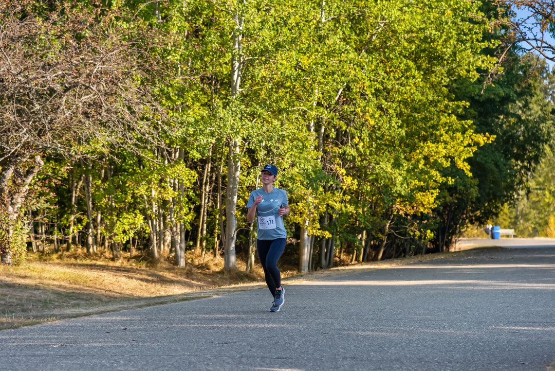 Woman enjoying a fall marathon run on a scenic tree-lined road.