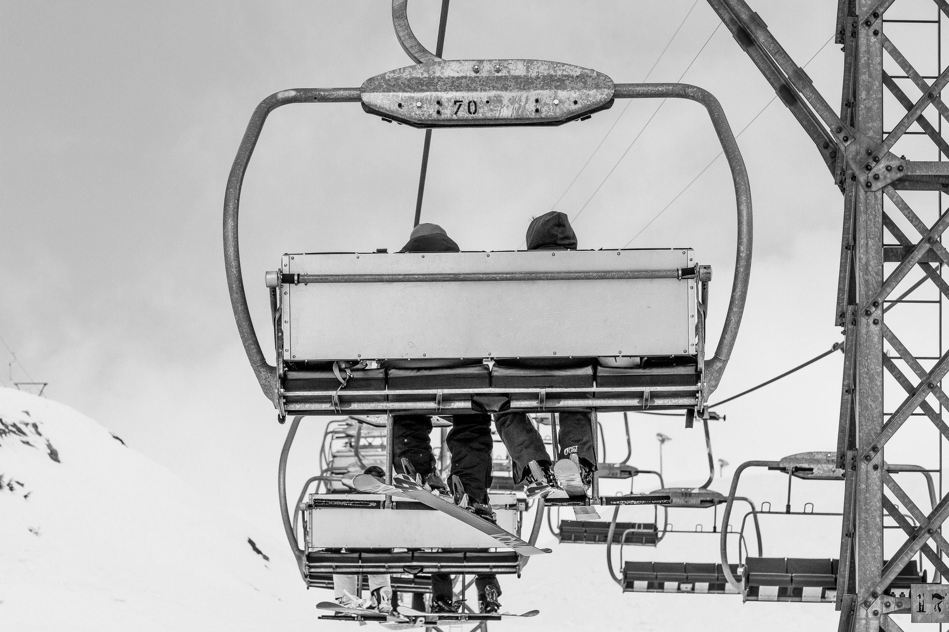 Black and white photo of a ski lift with people in the snowy Swiss Alps.