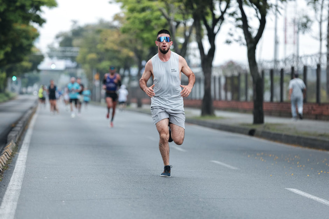 Athletic man in a gray outfit running on a city road during a marathon event